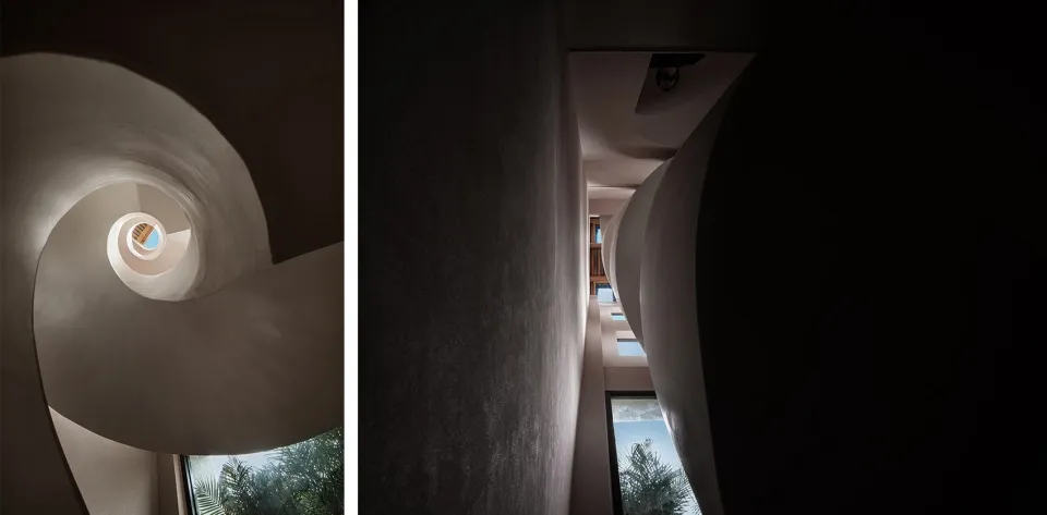 A spiral staircase with concrete walls and a window at the top