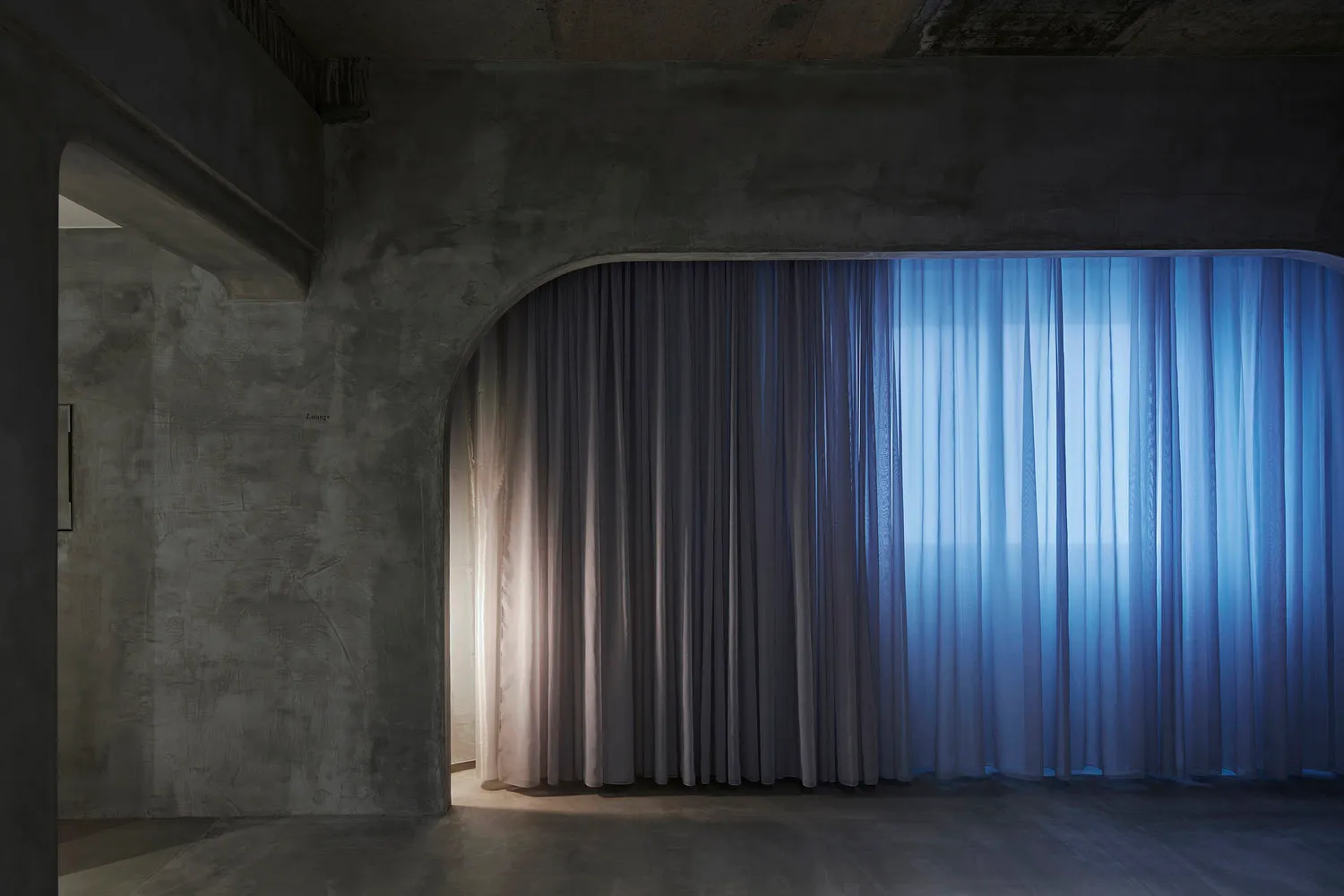 A modern interior design featuring luxurious drapery and concrete architectural elements.