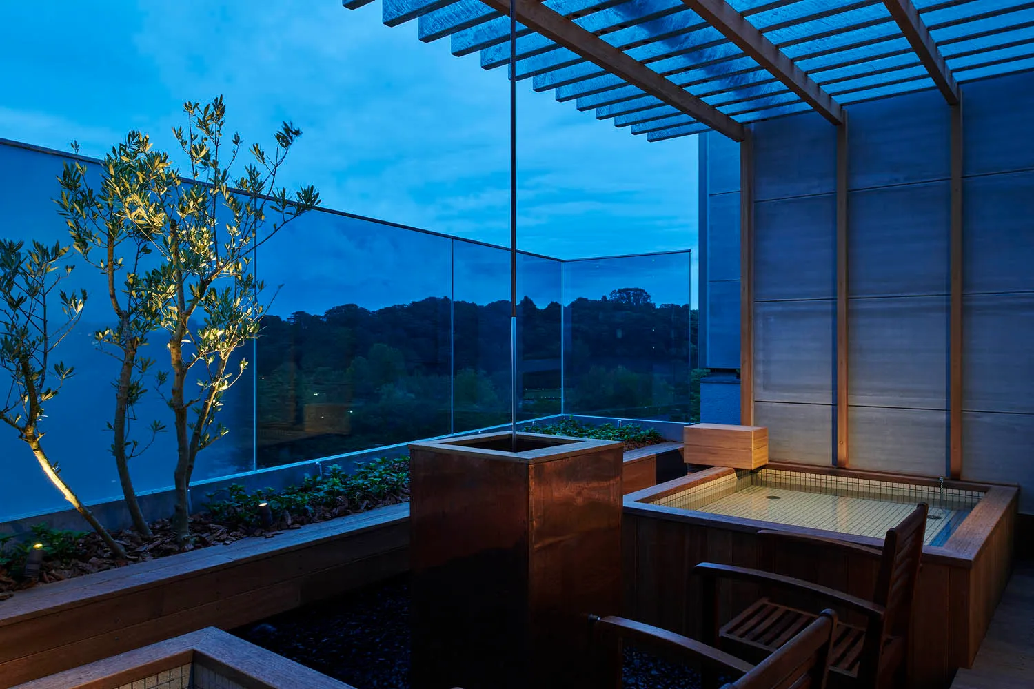 Modern balcony featuring glass windows and a wooden pergola at dusk.