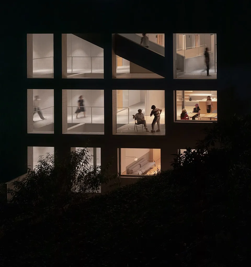A modern residential building exterior with large windows and a combination of glass and concrete materials.