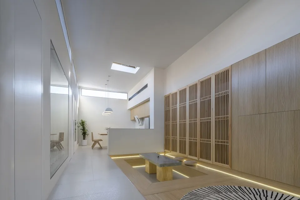 A minimalist interior design featuring white walls, wood accents, and stone elements.