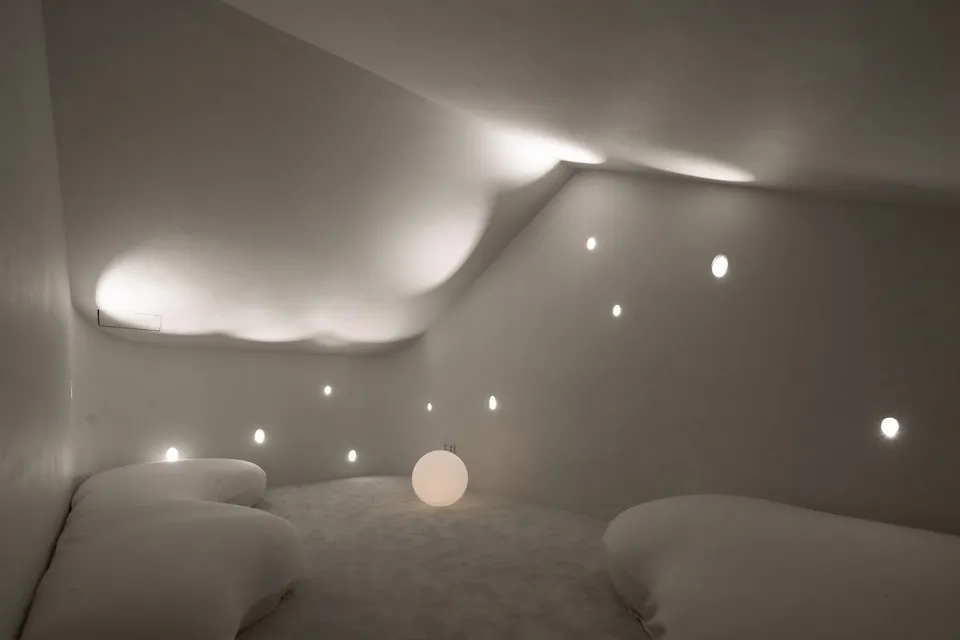 A minimalist white interior space with textured concrete walls and ceiling.