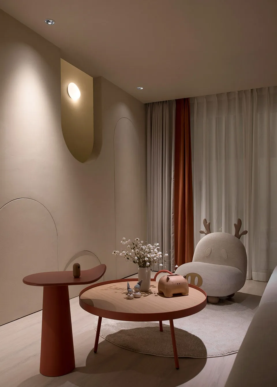 A modern living room featuring a rounded coffee table, a small side table, and a unique, plush armchair with antlers.