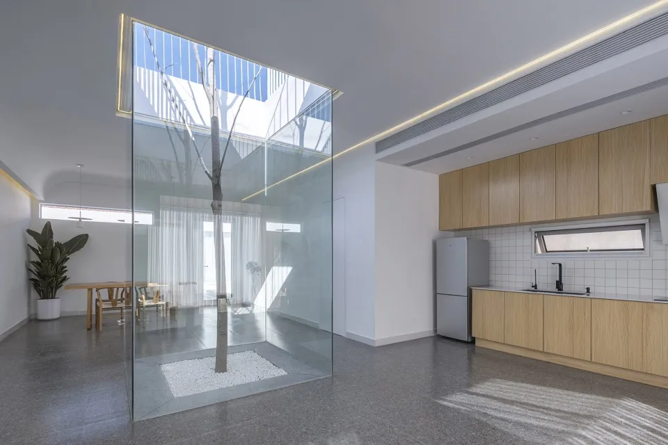 Modern minimalist kitchen with glass walls and wooden cabinets.