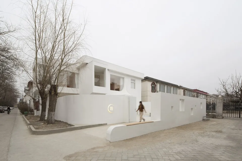 A modern minimalist architecture exterior with a white rendered concrete facade and large windows.