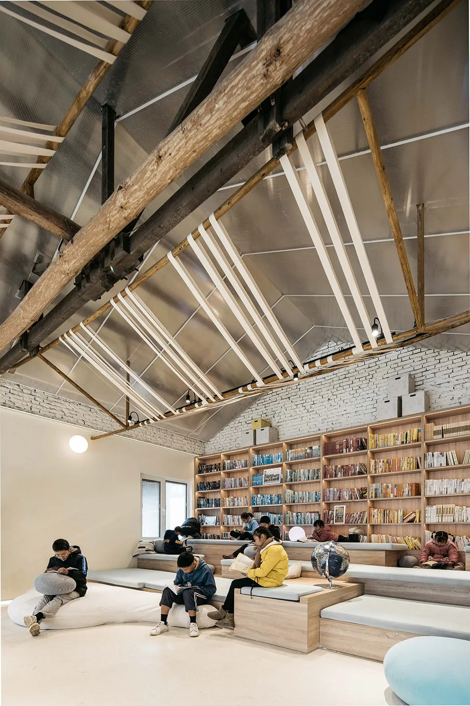 人們在現代圖書館閱讀書籍,露出木樑、金屬裝飾與混凝土地板。