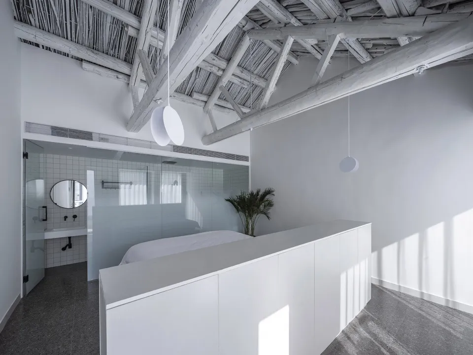 Modern minimalist bedroom featuring concrete floor and wooden ceiling beams.