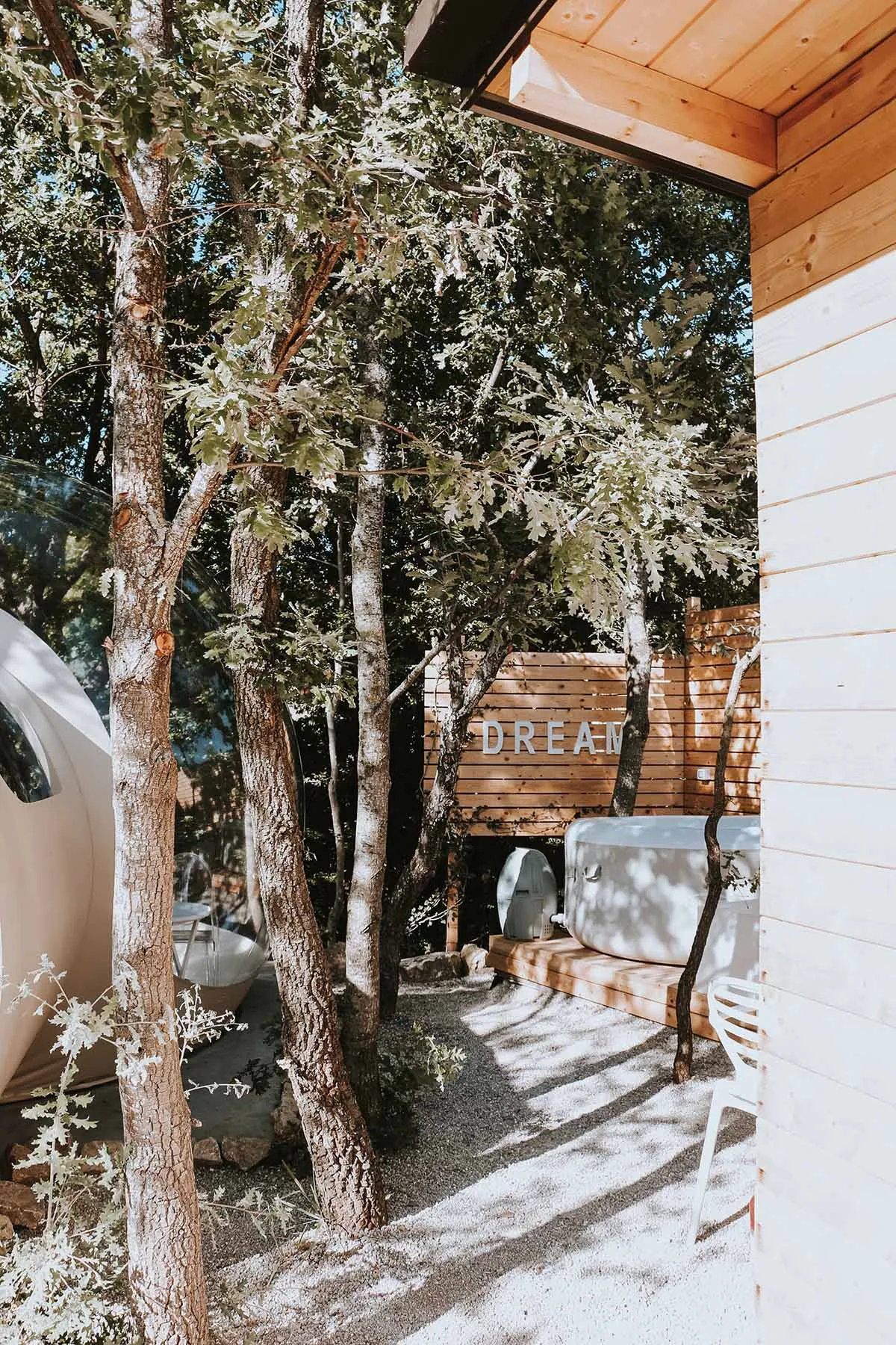 A minimalist outdoor living area featuring a wooden deck surrounded by trees and plants.
