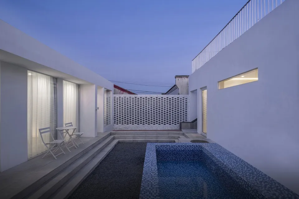 A contemporary patio with concrete floors, glass walls, and a pool.
