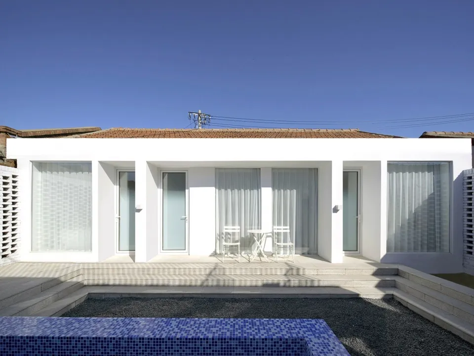 Modern residential property with glass walls and a concrete patio.