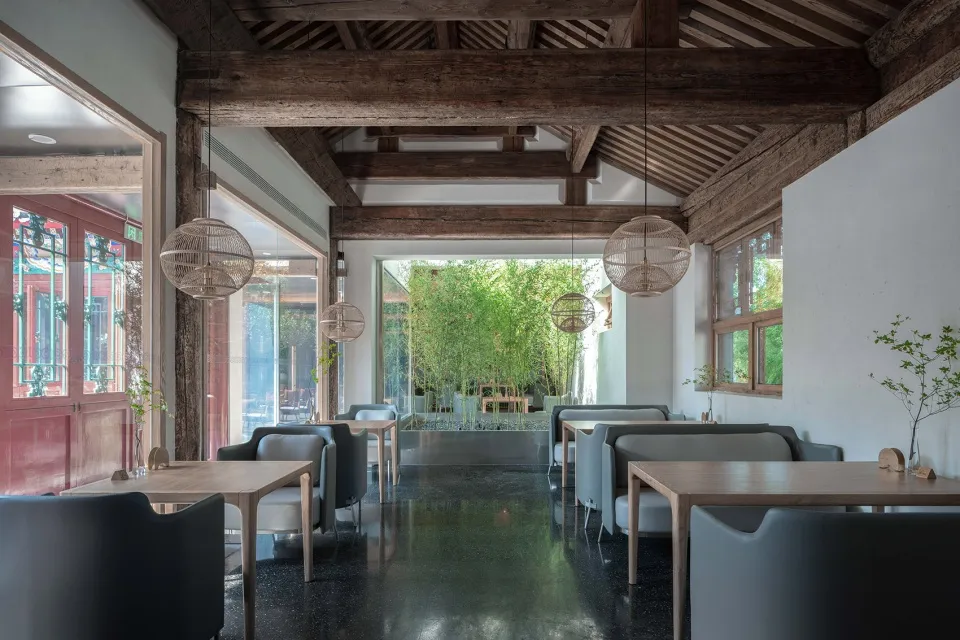 Modern restaurant interior with concrete flooring and bamboo plants.