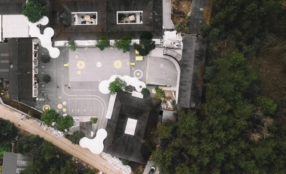 Aerial view of a modern school ground plan with concrete and asphalt surfaces and artificial trees.