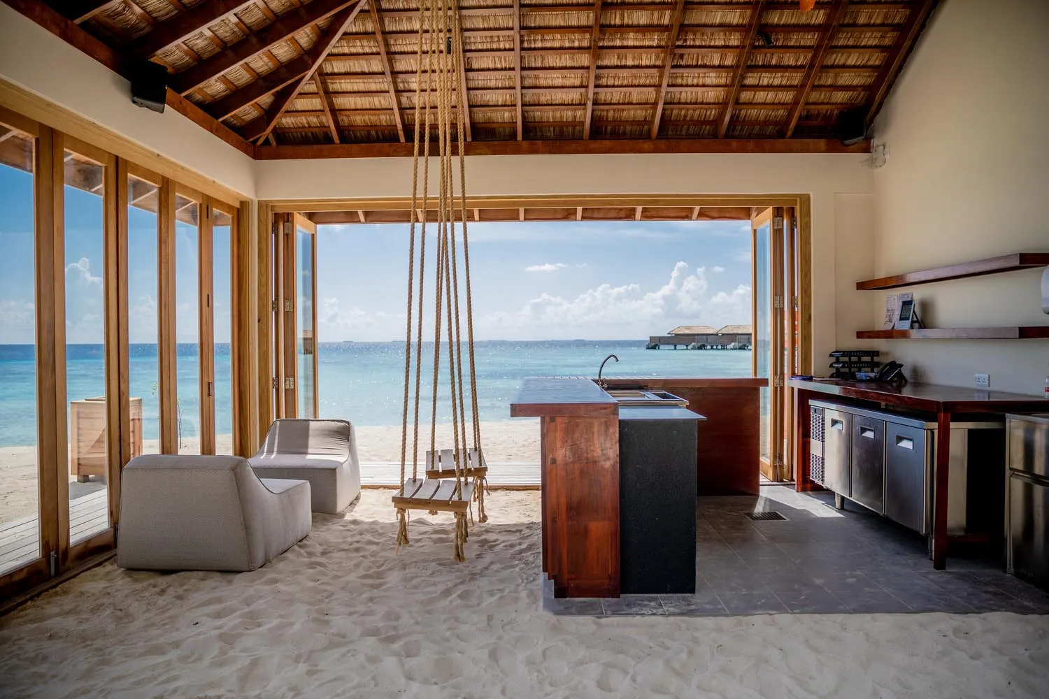 Minimalist residential kitchen with wooden finishes and a view of the ocean.