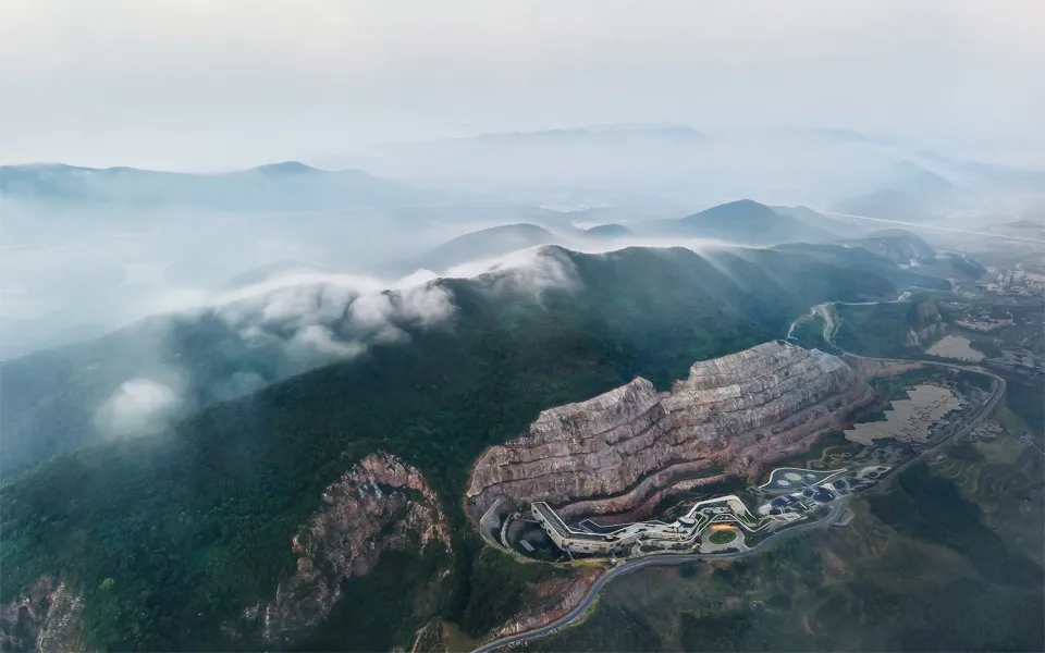 礦場的俯瞰視角,層疊岩層與山巒旁的雲層。