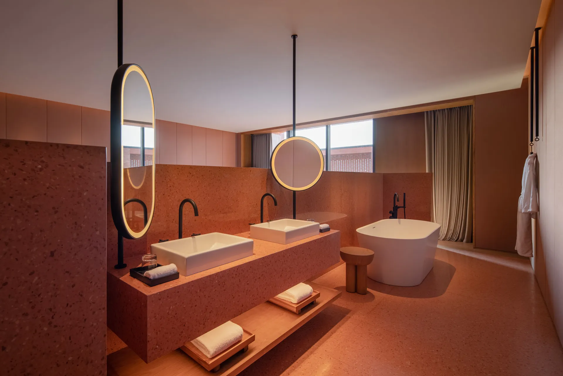 Modern bathroom interior with neutral-toned materials, sinks, and bathtub.