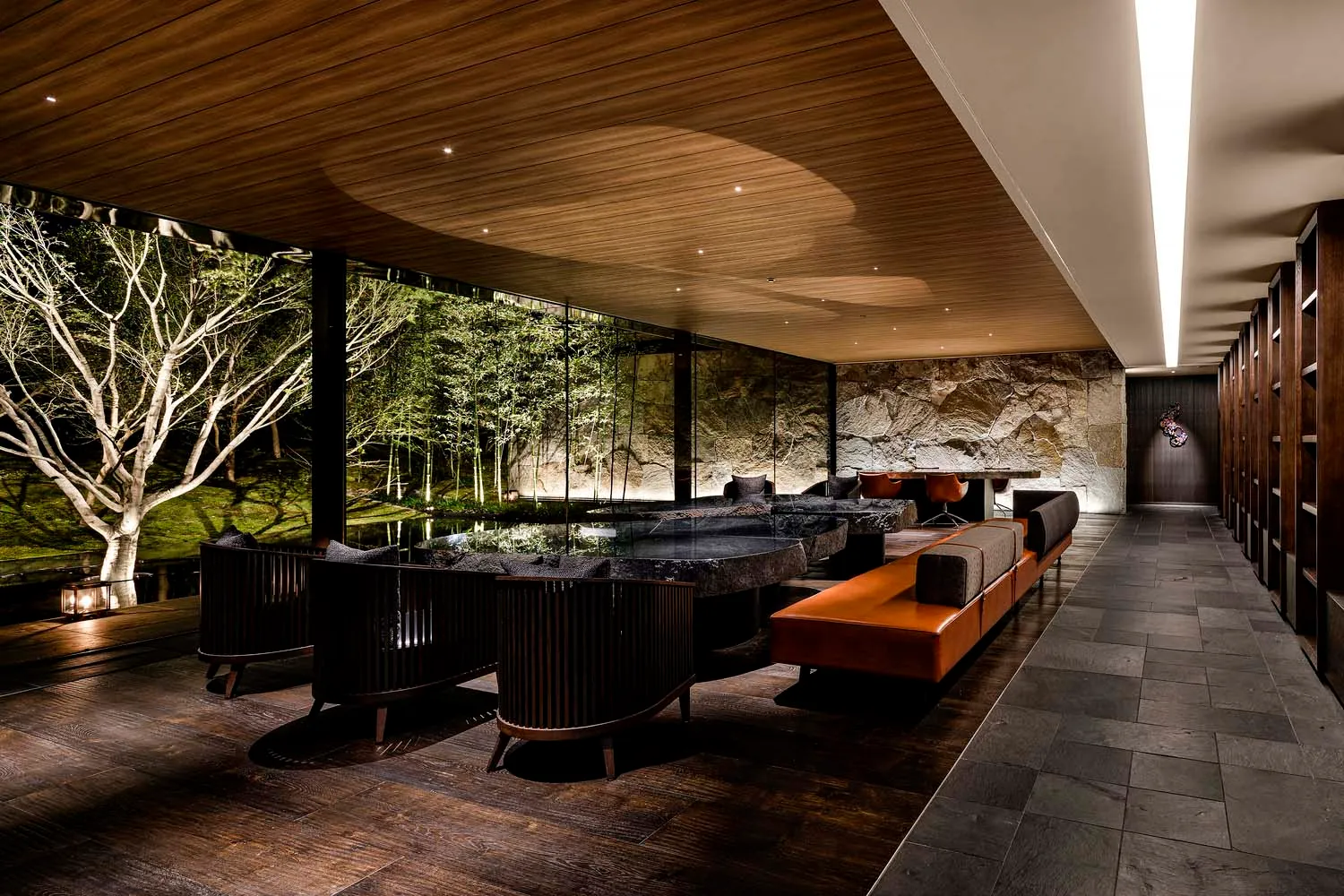 Modern hotel suite with contemporary interior design, featuring wooden furnishings, concrete accents, and a glass wall.