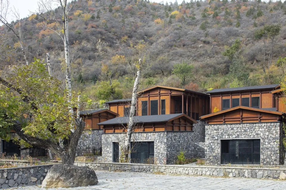 Modern residential houses with rock walls and wooden accents nestled in a valley.