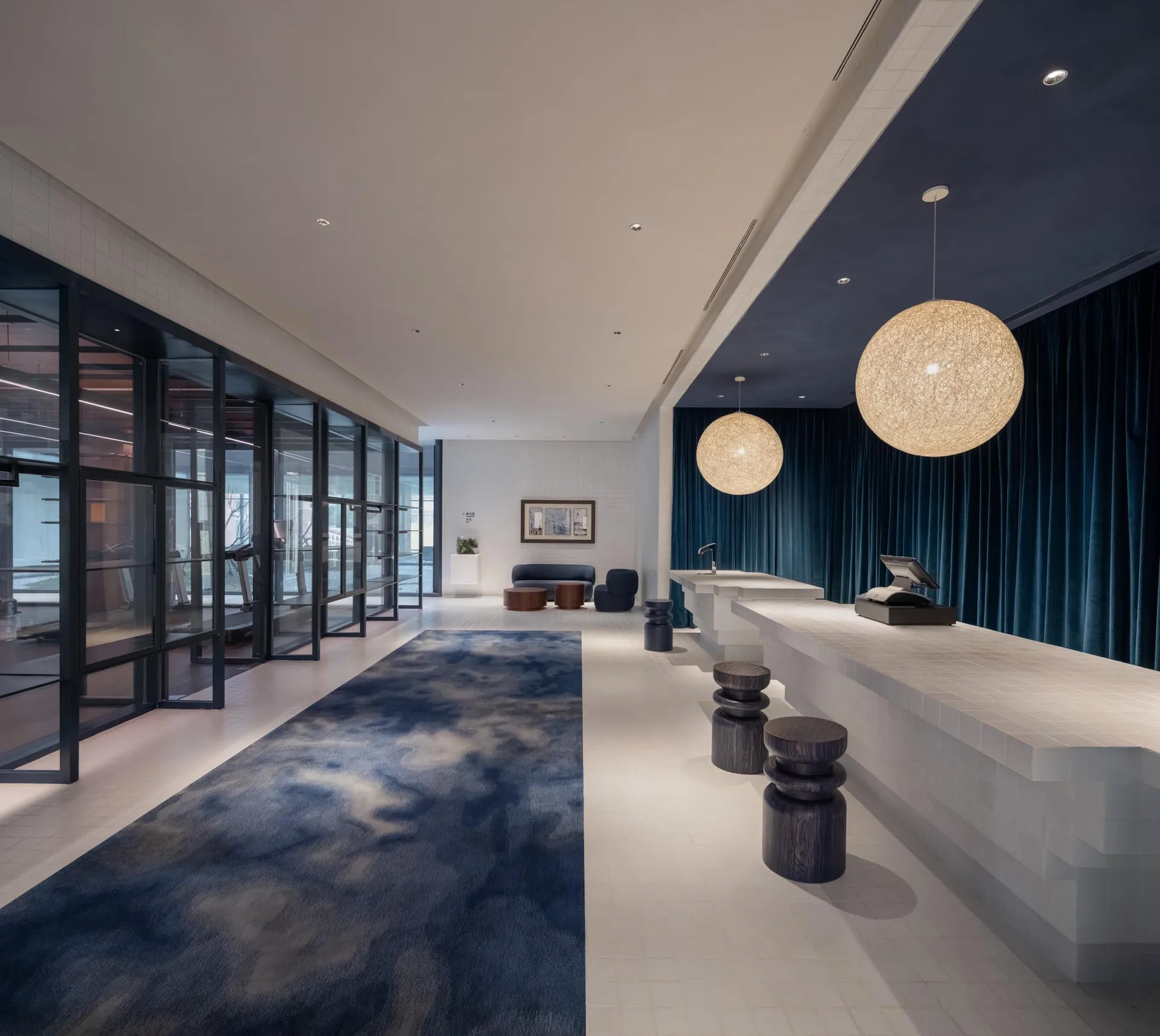 Modern lobby with tiled flooring, concrete seating, and stools