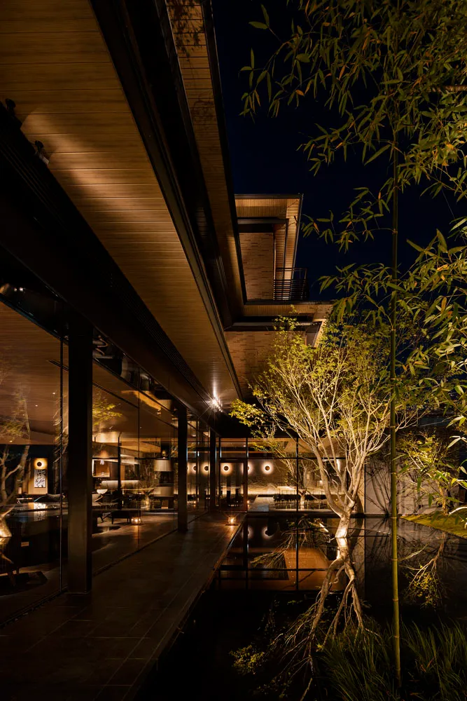 A modern residential exterior illuminated at night with wooden and glass structures.