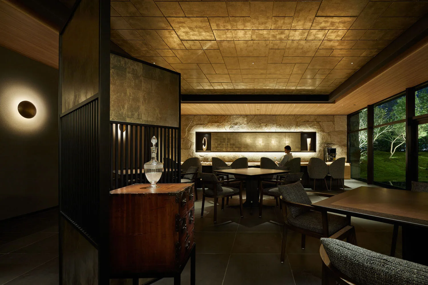 Modern restaurant interior with wooden tables, stone accents, and metal decor.