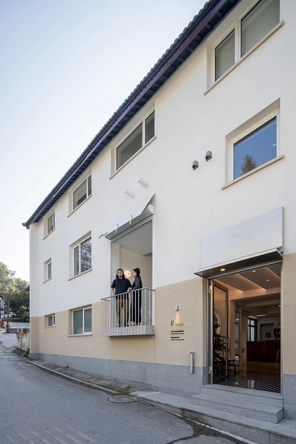 Modern building with concrete exterior features a balcony and large windows.