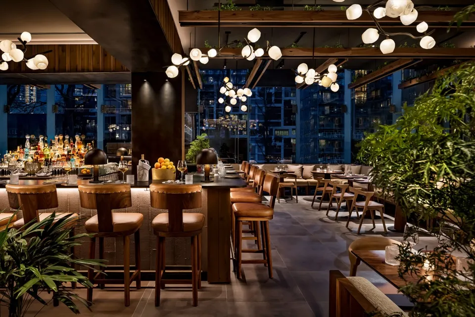 A modern restaurant bar interior with wooden furniture, glass shelves, and metal accents.