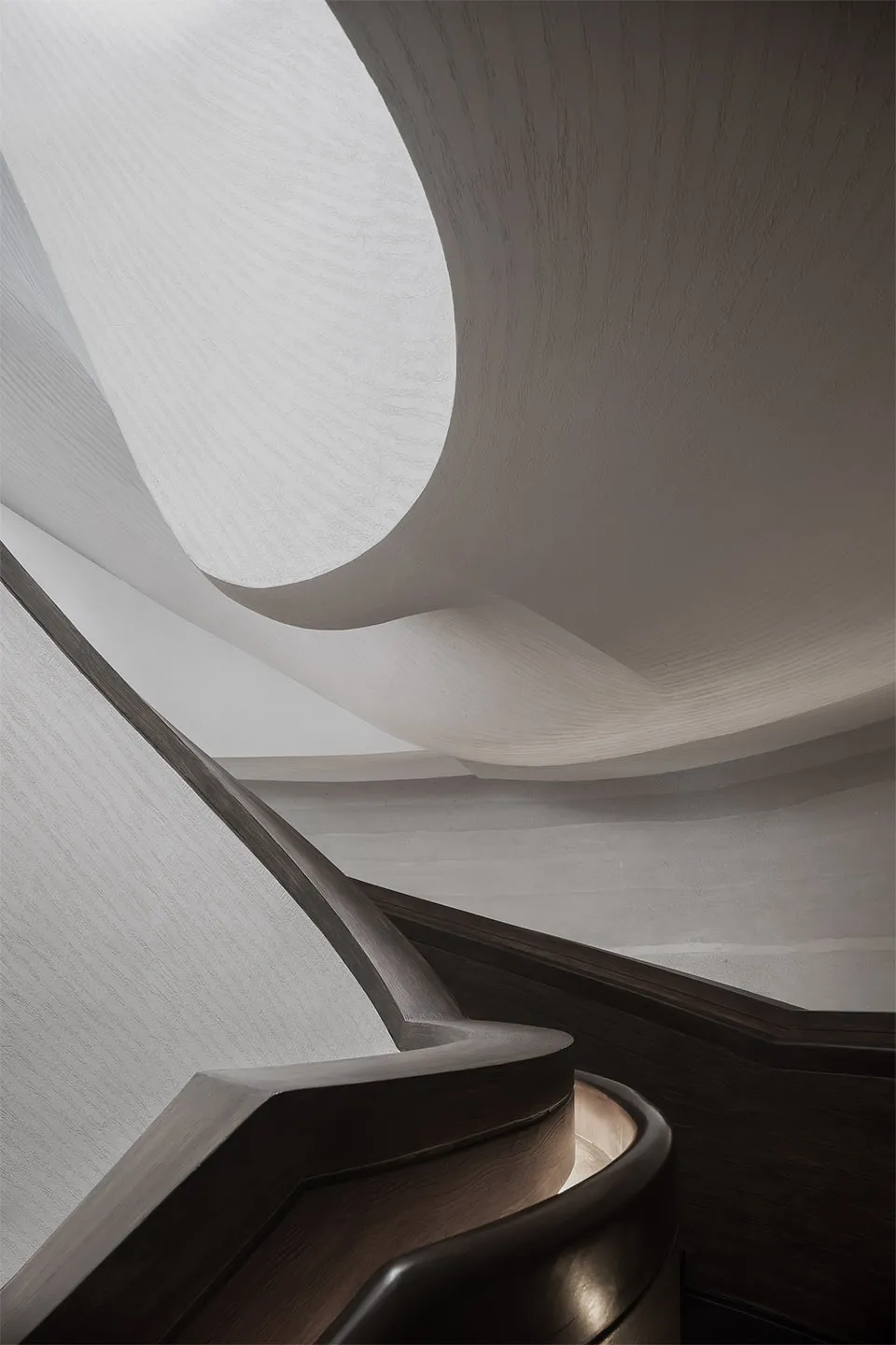 A modern staircase with wooden railings and a curved design.