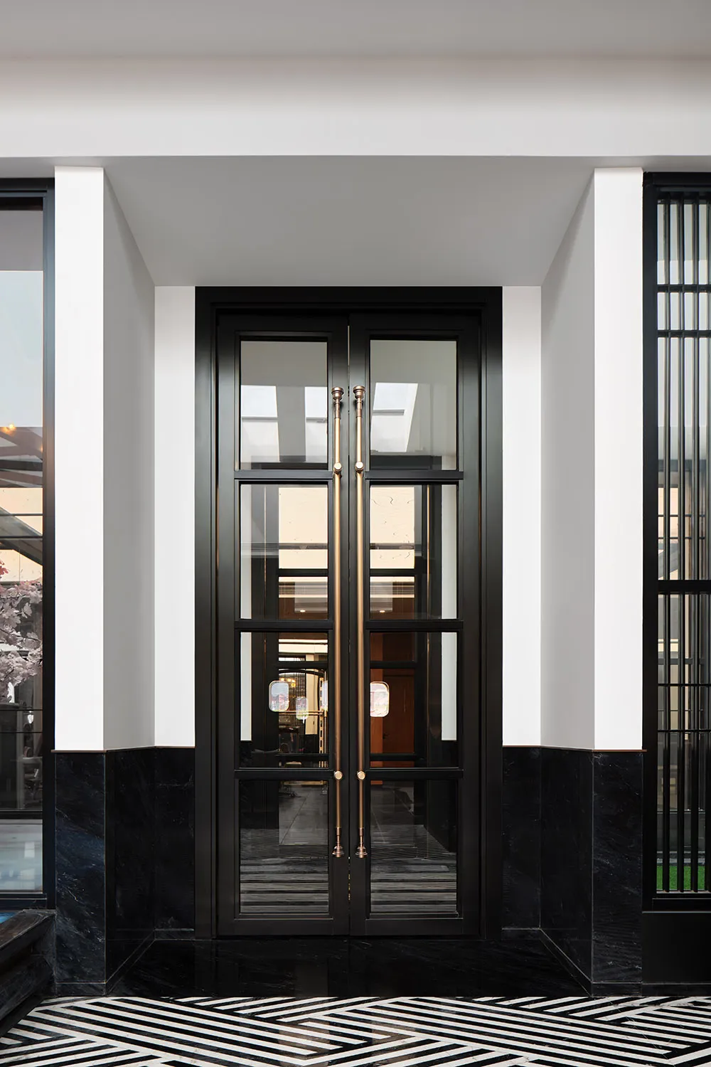 Modern black glass double doors with brass handles and marble accents