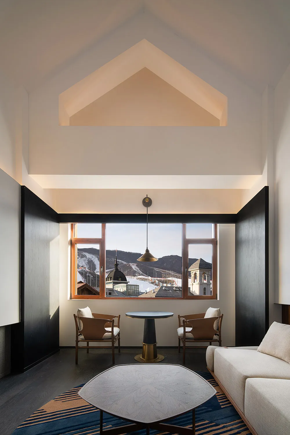 A modern interior living room with a view of a snowy landscape through a large window.