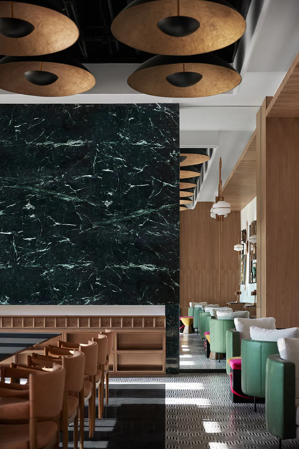 Modern restaurant interior featuring a marble wall and wooden tables.