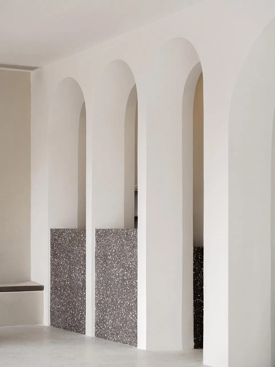 A modern interior with concrete arches and textured walls