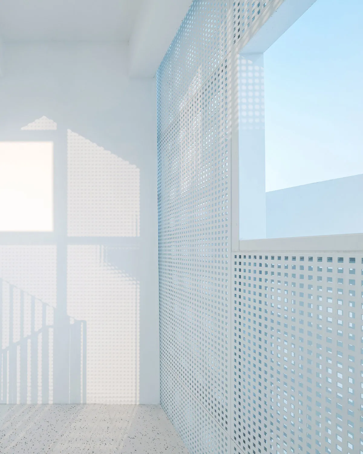 A minimalist interior with a metallic grid wall and natural light.