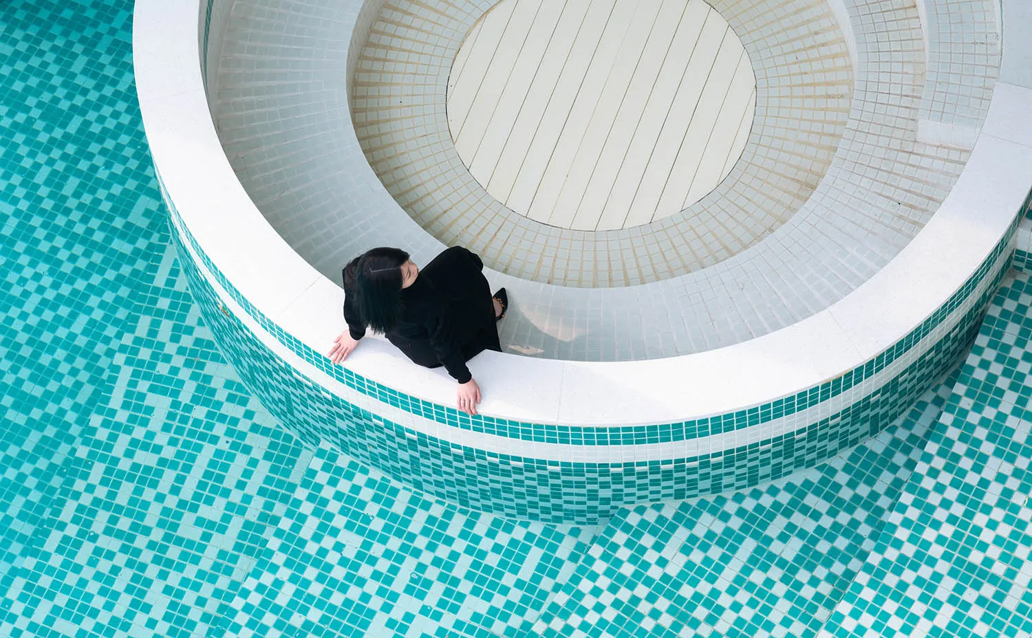A modern swimming pool with blue tiles and a white circular structure.