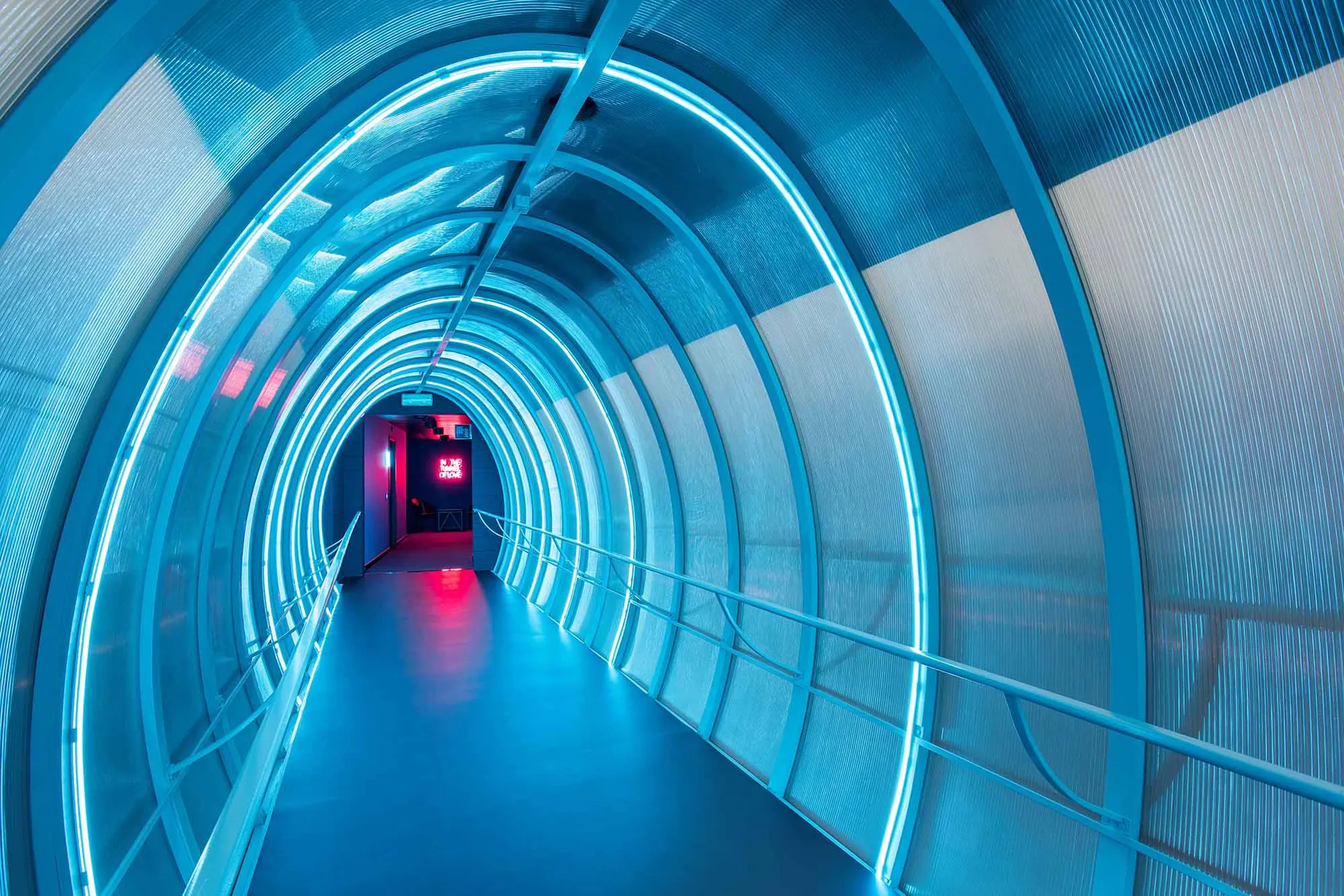 A futuristic tunnel constructed with metallic materials and illuminated internally.