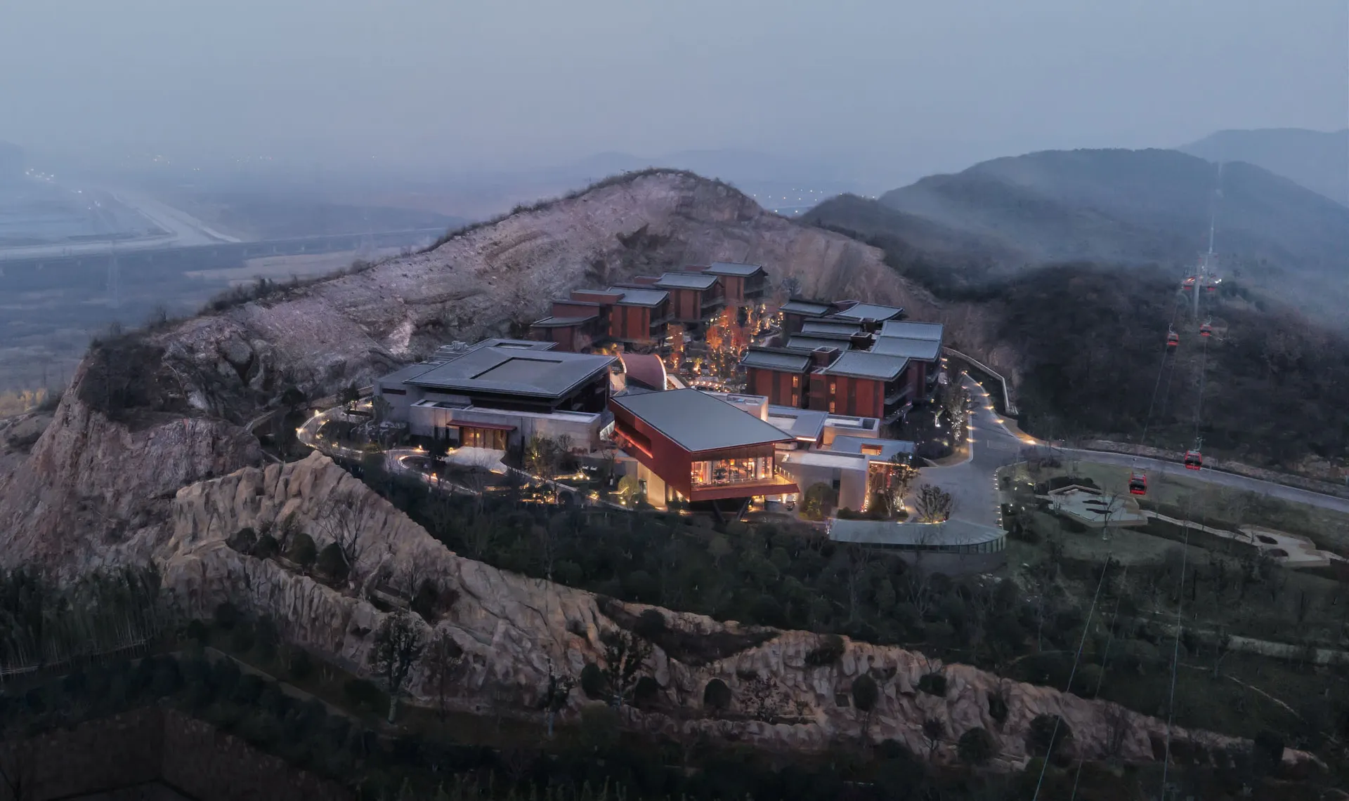 A resort with modern architecture, featuring wooden structures with glass windows at dusk.
