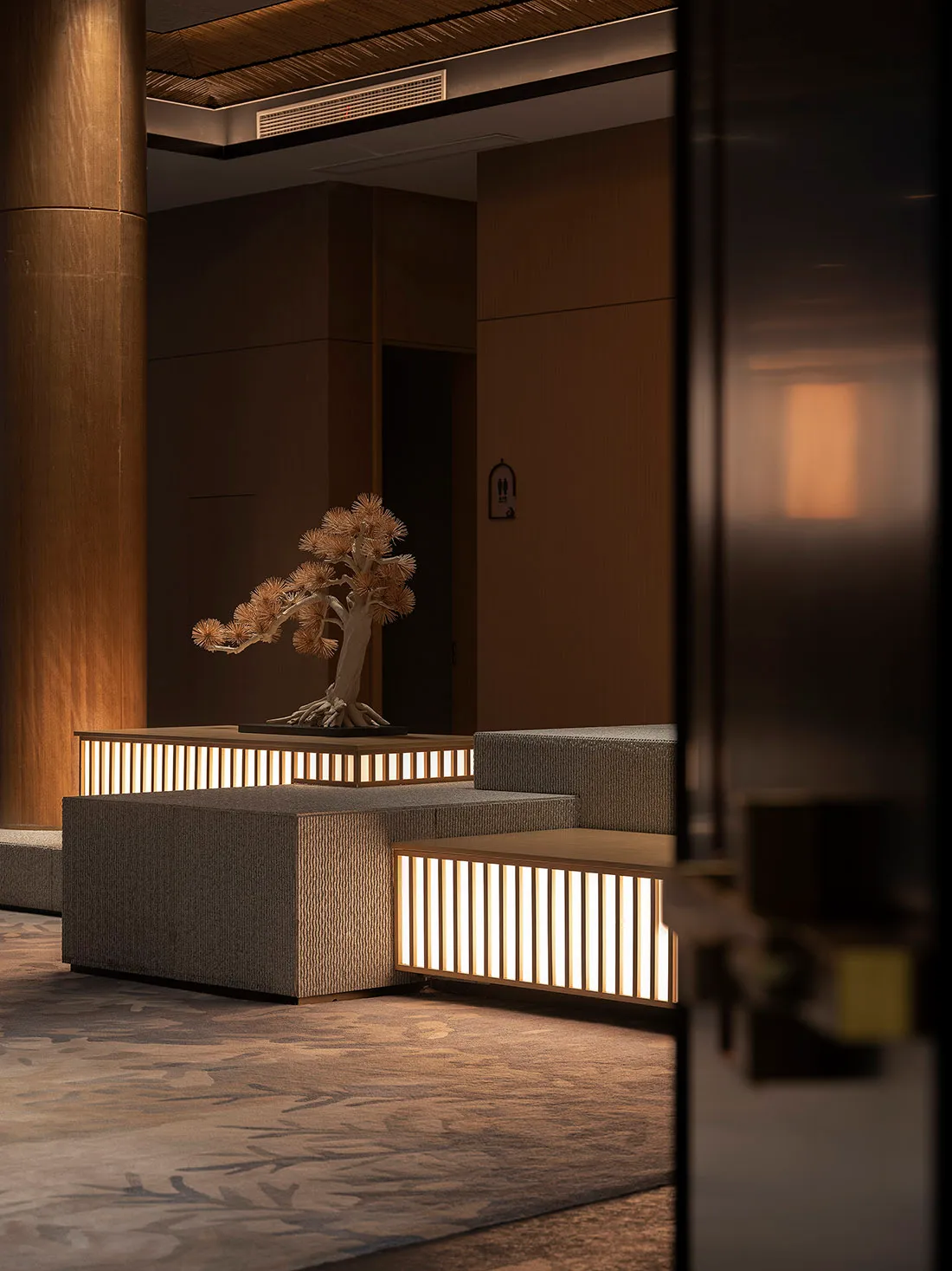 Modern lobby featuring concrete walls and natural lighting, illuminated by soft, ambient light, with a minimalist design and 