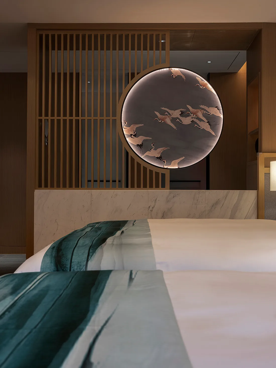 Modern minimalist bedroom with a bed featuring a fabric headboard placed against a marble and wooden wall with a circular dec