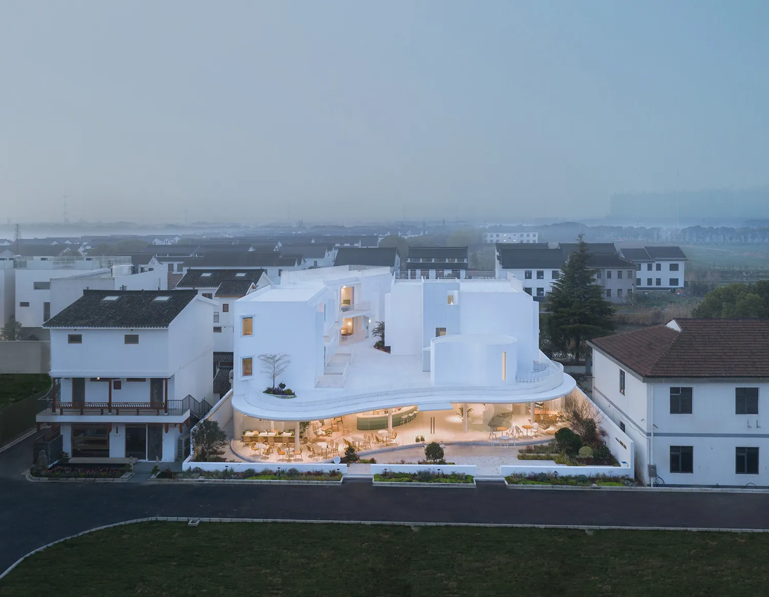 An aerial view of a modern building with a contemporary design, featuring extensive use of concrete and glass materials.