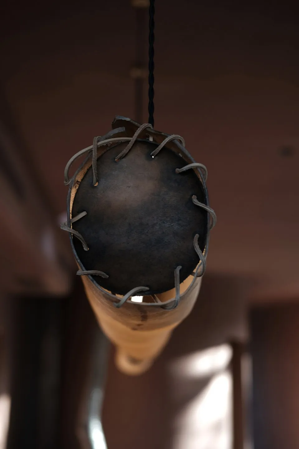 Metallic industrial-style pendant light with leather straps and a black spherical shade.