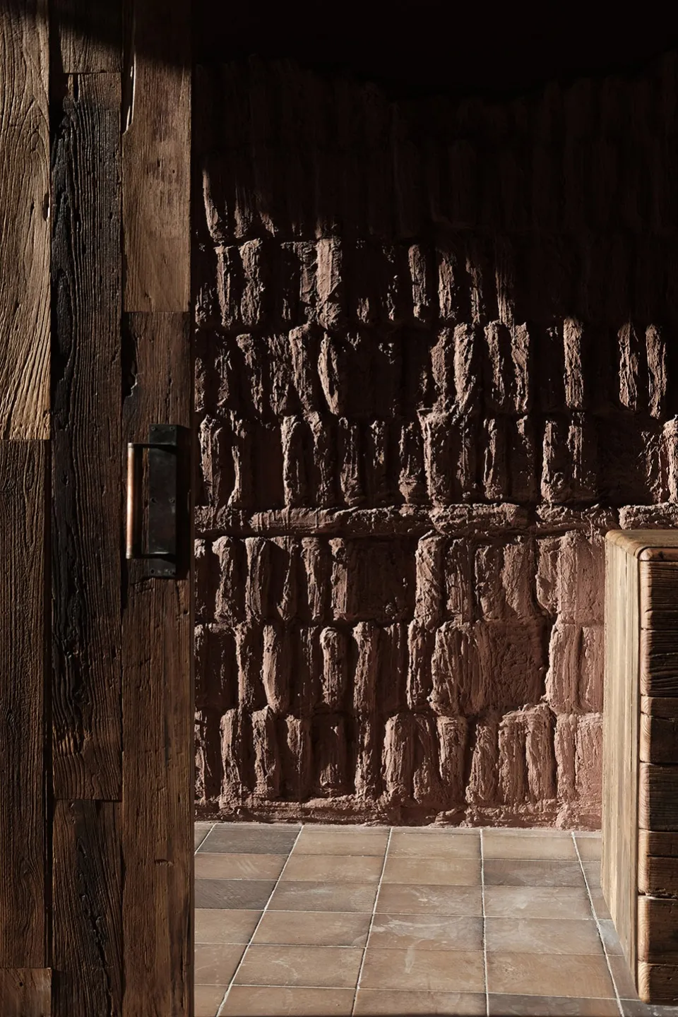 A wooden panel wall next to a clay brick textured wall in an interior space.