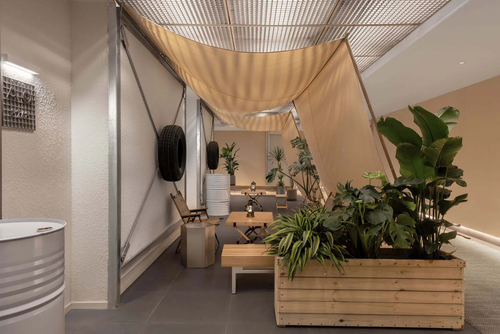 Industrial-style cafe interior featuring wooden planters, concrete furniture, and exposed concrete walls.