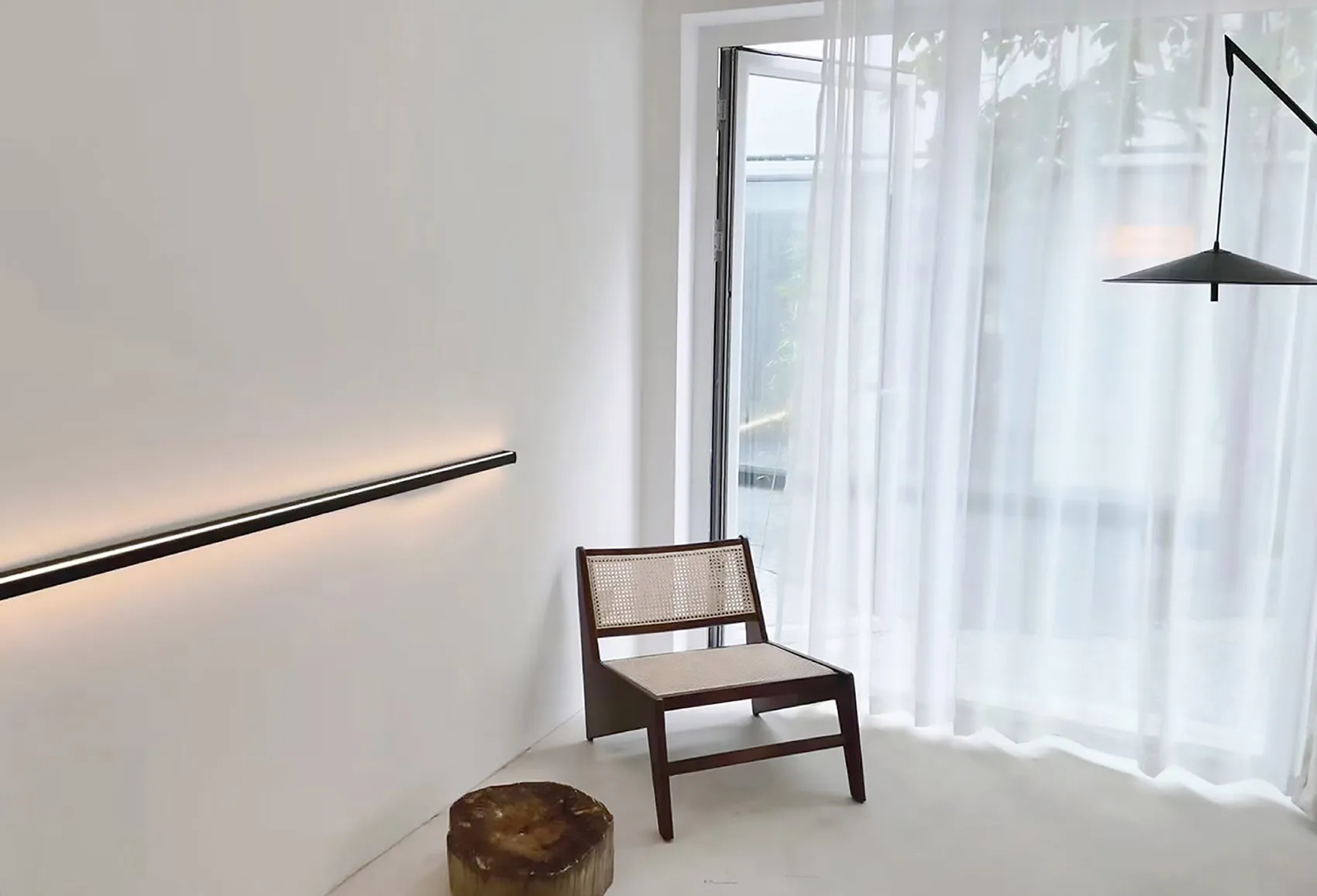 A minimalist interior featuring a large glass window and wooden furniture.