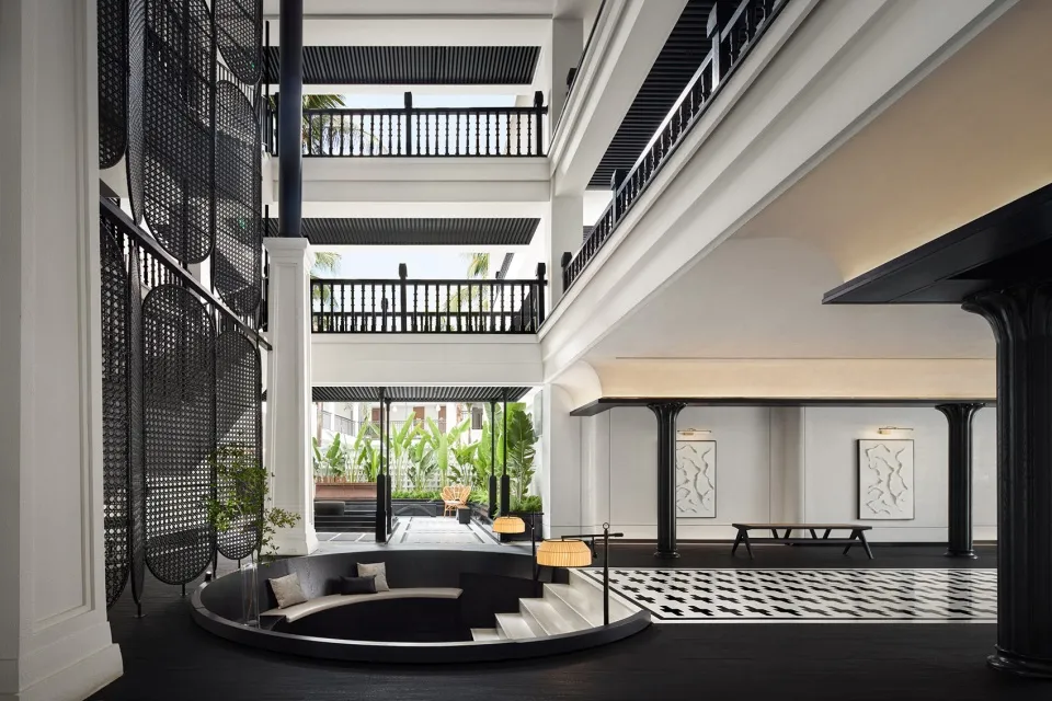 Modern hotel lobby with black glass accents, black glass railings, and stone columns.