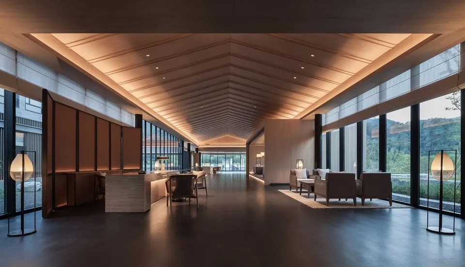 Modern hotel lobby with wood paneling, glass windows, and concrete flooring
