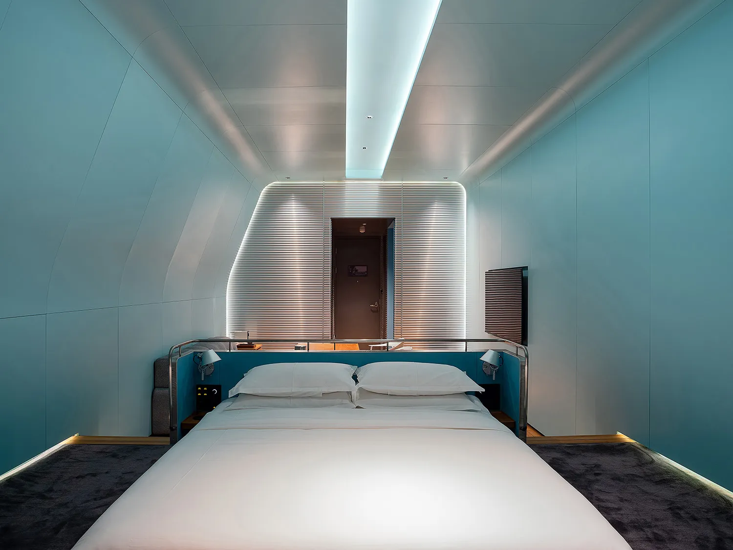 A minimalist bedroom featuring metallic walls and ceiling, with a large bed and bedside lamps.