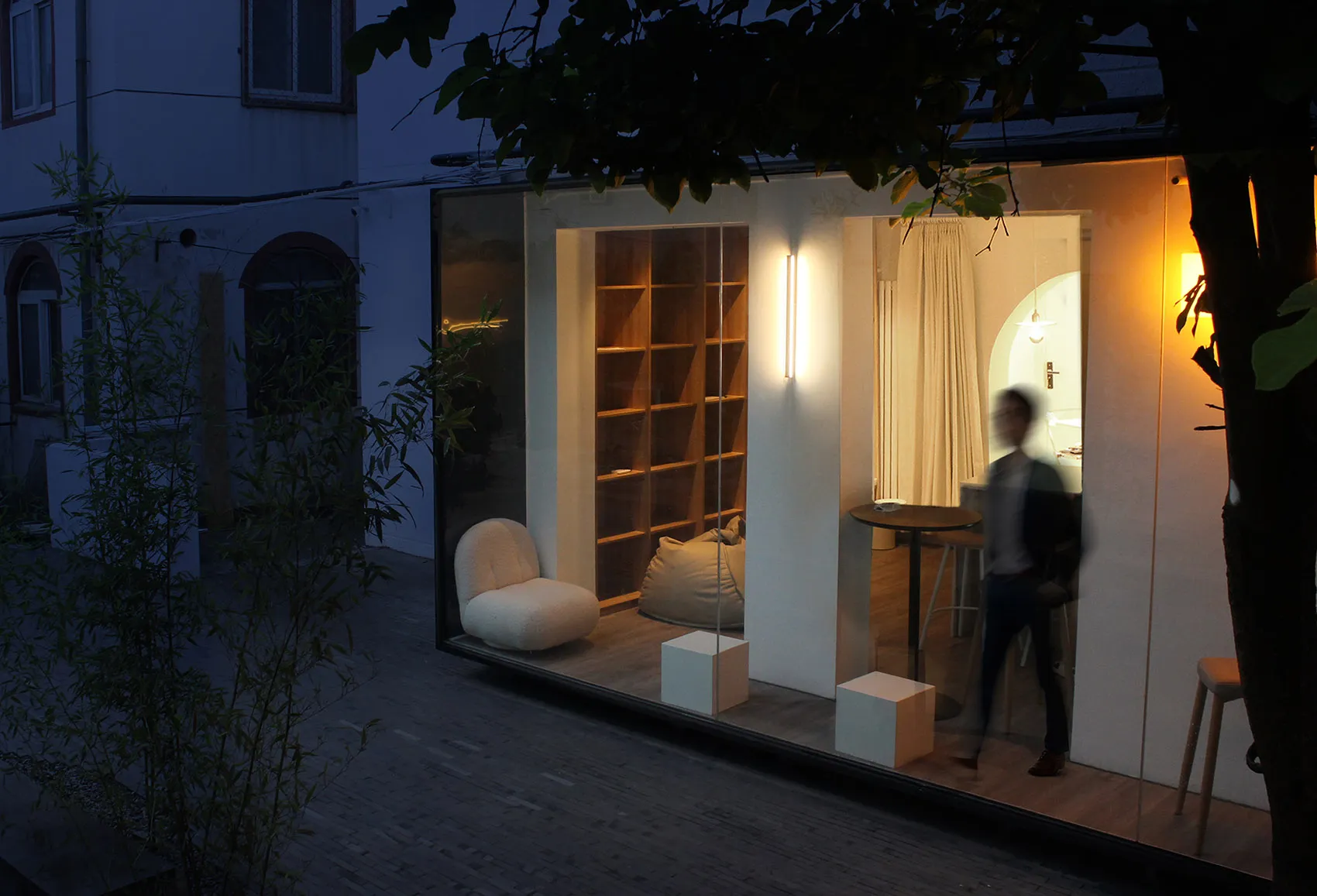 A modern retail storefront with a large glass wall and lit interior at night.