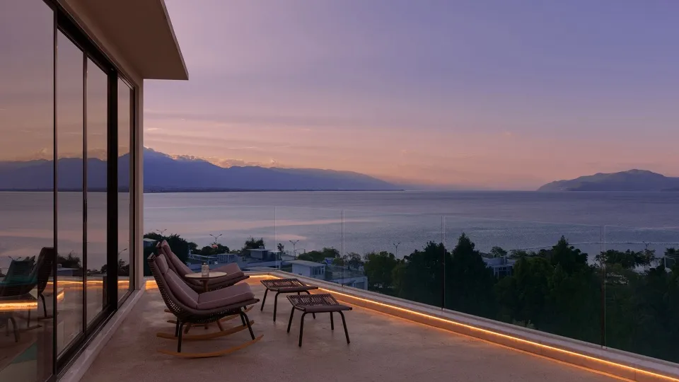 A spacious balcony featuring a luxurious view of the ocean and distant mountains at sunset.