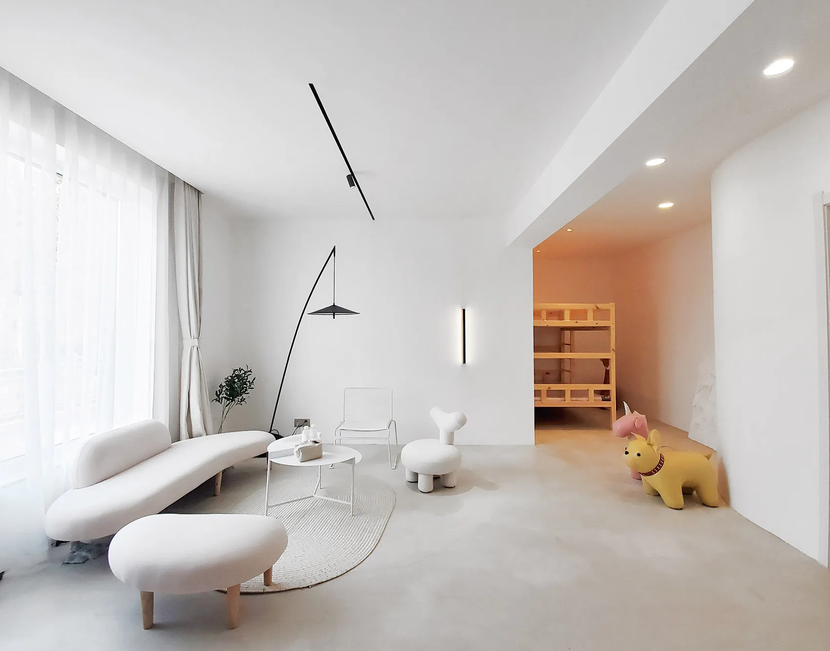 A minimalist living room with white furniture, modern light fixtures, and simple decor.