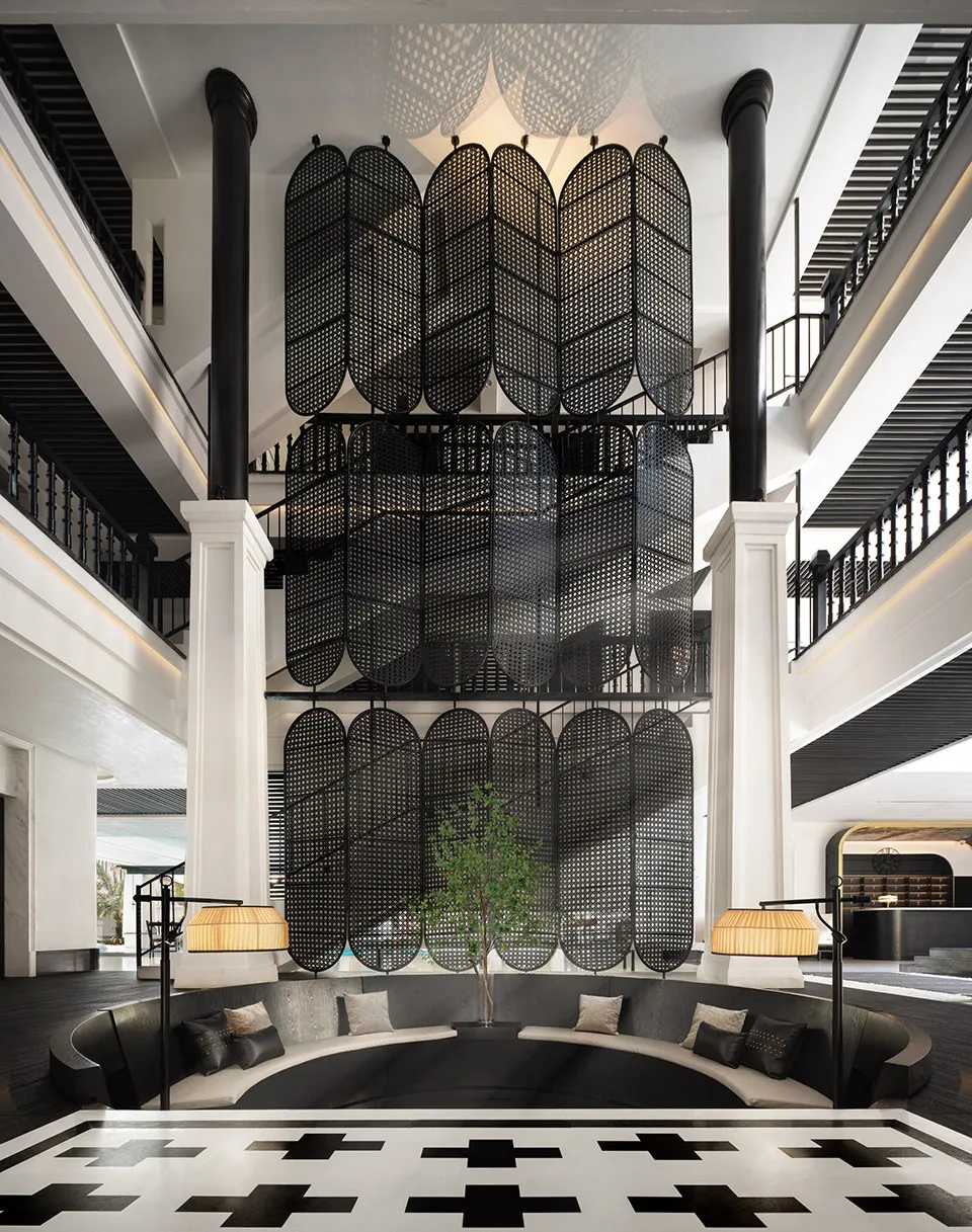 A modern hotel lobby featuring a black metal and wood design with a large planter and seating area.