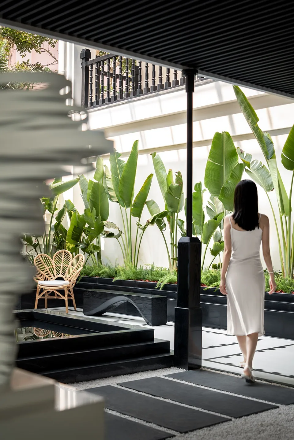 A modern residential interior featuring lush green plants on a black and white checkered floor.
